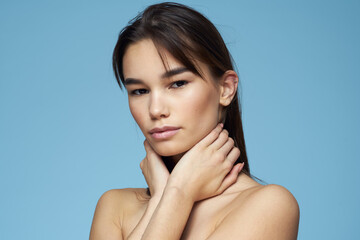 brunette with bare shoulders cosmetics close-up skin care blue background