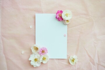 ピンクの不織布に梅の生花でデコレーションした長方形の白紙のカードのモックアップ、縦置き