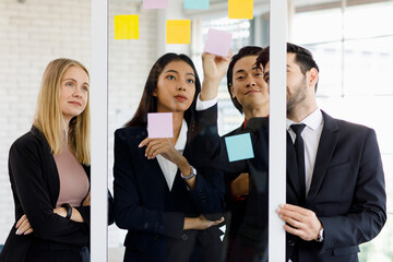 Caucasian Businesswomen and Asian Businessmen smiling explaining working smilling and on a board, having post-it papers at the conference room in the office. Concept meeting consult teamwork.