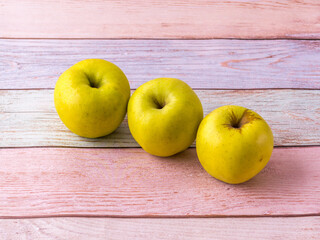Three apples on the table. A row of fruits.