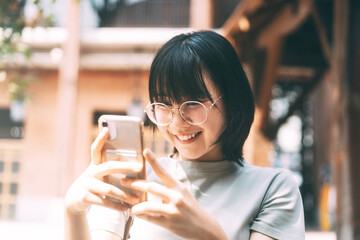 Young adult happy asian woman wear eyeglasses using mobile phone for social media.