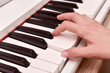 Obraz premium Woman's hands playing electronic digital piano at home. The woman is professional pianist arranging music using piano electronic keyboards. Musician practicing keyboard composing music