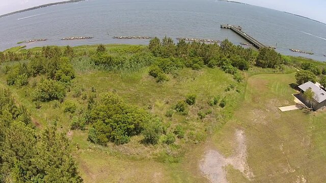 Drone shot tracks along shoreline showing fishing pier and Delaware State Park facilities.  Boy kicks soccer ball.