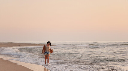Fototapeta na wymiar woman walking on the beach at sunset