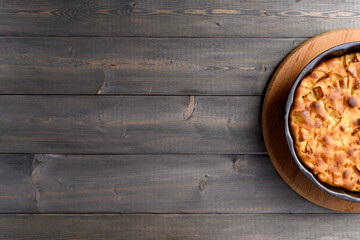 Apple pie in a round shape on a wooden background. Apple charlotte