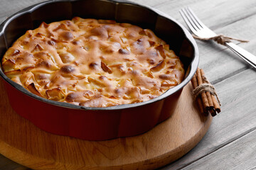 Apple pie in a round shape on a wooden background. Apple charlotte