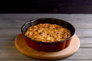 Apple pie in a round shape on a wooden background. Apple charlotte