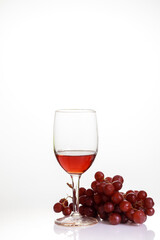 Red wine in glass with red grape.