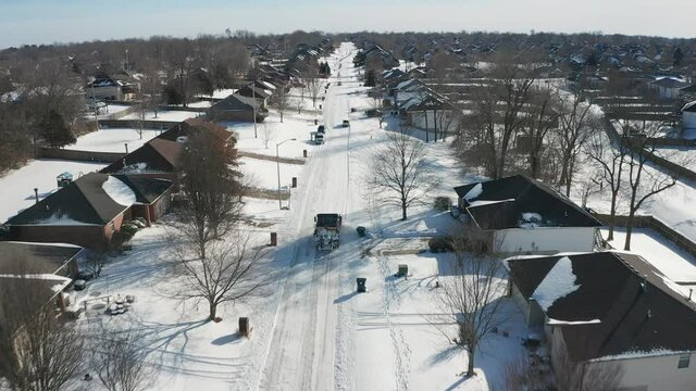Aerial view of a snow plow clearing streets in a suburban neighborhood