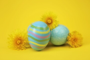 Easter holiday.Blue striped  Easter eggs, yellow dandelion flowers on a yellow background.Spring religious holiday background. copy space. 