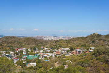 Xiamen city skyline, view from the mountain with a small village on the mountain and modern city skyline in distance by the sea
