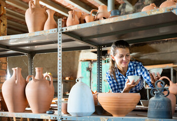 Female artisan in apron having ceramics in stock. High quality photo