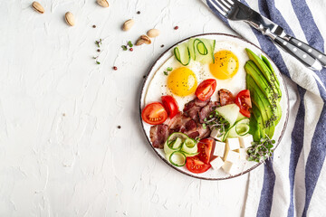 Plate with a keto diet food. paleo keto breakfast fried eggs, bacon, avocado, cheese and fresh salad. Keto, paleo breakfast. Top view, copy space
