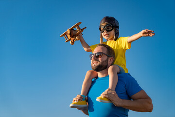 Father and son playing against blue summer sky background