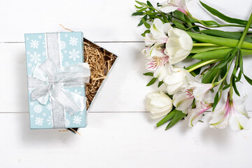 composition of white flowers and an ajar gift box on a white wooden background. holiday and congratulations concept