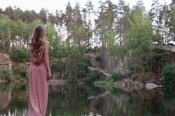 Fototapeta na wymiar blonde girl with long beautiful hair in a pink dress on a forest background