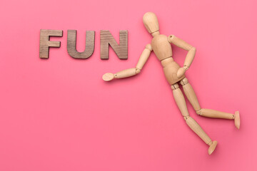 Wooden mannequin with word FUN on color background