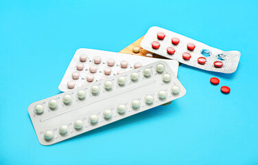 Strips of different birth control pills on color background