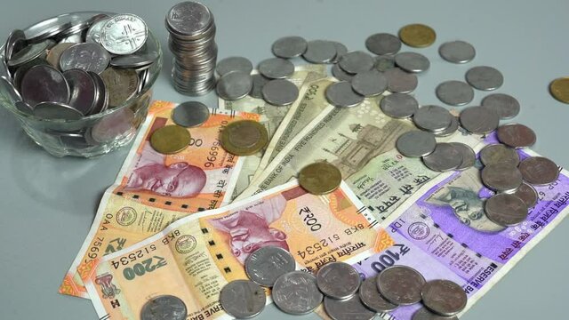 Slow motion shot of indian money rupees coins falling over currency notes