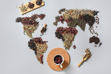 World map made of different sorts of tea and cup with dry hibiscus on light background