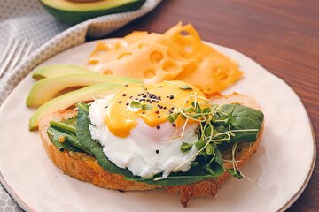 Tasty sandwich with florentine egg, avocado and cheese on wooden background, closeup