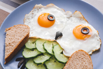 Creative breakfast for children with eggs, toasts and fresh vegetables on table, closeup