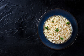 Rice with parsley, top-down shot on a black background. Easy side dish
