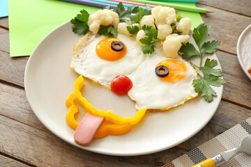 Creative breakfast for children with eggs, fresh vegetables on wooden background, closeup