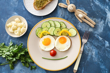 Creative breakfast for children with eggs, bread and fresh vegetables on color background