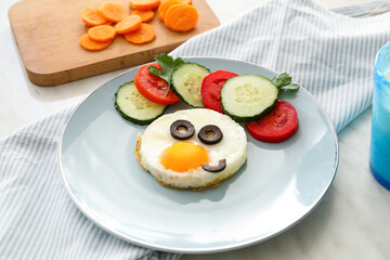 Creative breakfast for children with egg and fresh vegetables on light table, closeup