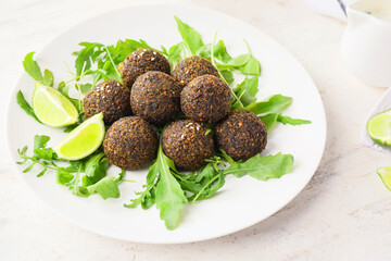 Plate with tasty falafel balls, arugula and lime on light background