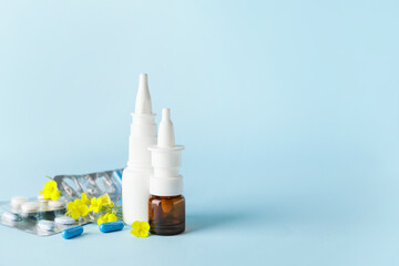 Bottles with drops, flowers and pills on color background