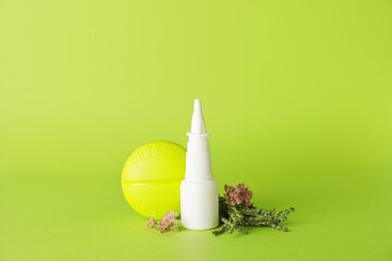 Bottle with drops, flowers and container for pills on color background