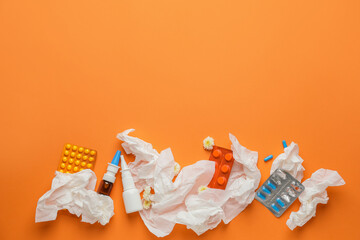 Bottles with drops, pills and used tissues on color background