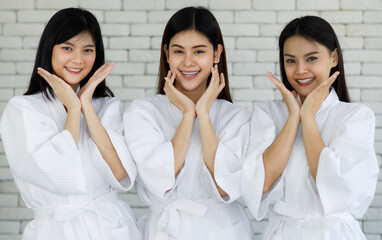 Portrait 3 asian adults women with long black hair wearing apa style white robes Smiling and looking at the camera her hands touched on her face looked happy with her skin face. Shoot in a studio room - obrazy, fototapety, plakaty