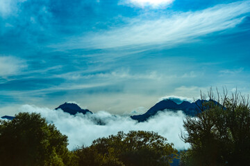 New Zealand high country mountains and bush shrouded by low cloud with wind-blow cloud above