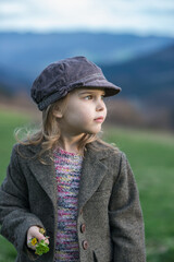 Lovely little girl with vintage clothes enjoying the spring sun among a spring green field