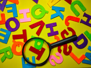 Selective focus.Magnifying glass and colorful word on yellow background.Education concept.Shot were noise and film grain.