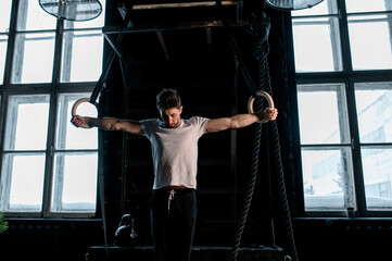 Fototapeta na wymiar Young Male Athlete With Gymnastic Rings In The Gym. focus on rings