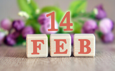 The holiday of February 14 on wooden cubes. Floral background in the background.