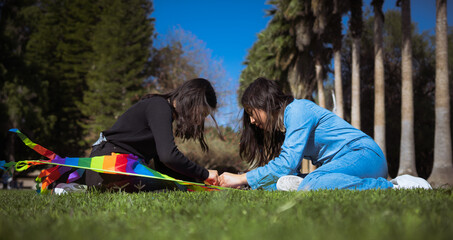 Girls preparing a kite sitting in a park