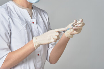 A nurse taking medicine into a syringe from a bottle close-up. Preparation of the coronavirus...