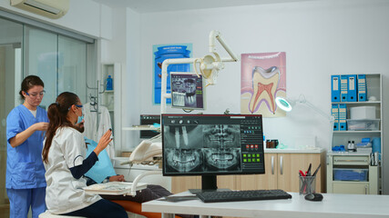 Dental doctor pointing on digital screen showing dental implants, preparing man for surgery....