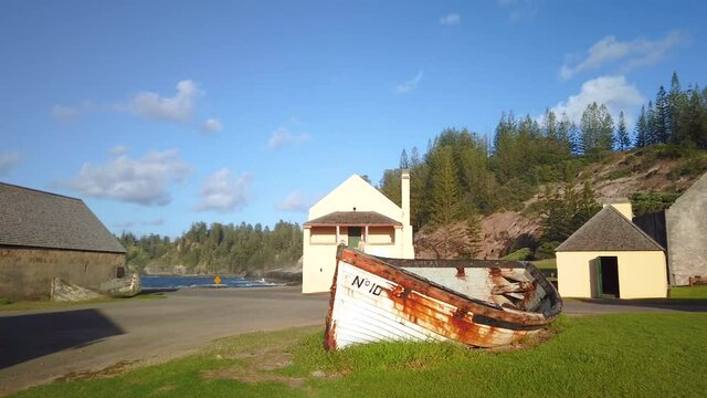 Left to right panning motion of old Norfolk Island Lighter boat at sunrise with the ruins of the old Crankmill and Pier Store Museum in background, Norfolk Island,Australia