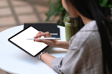 Young creative designer holding stylus pen drawing on screen of digital tablet while sitting at the park.