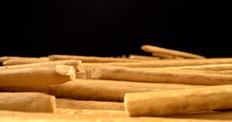 Light brown grissini on black background. Tasty appetizers for homemade food. Baking, Food, Taste. Close up. High quality photo.