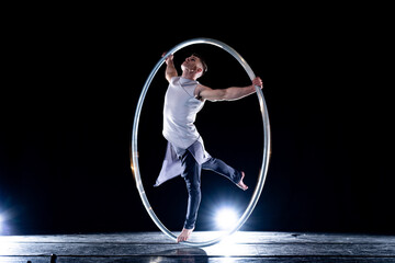 Fototapeta na wymiar Cyr Wheel circus artist on smoked, dark background performing on stage 