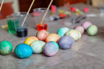 Dozen colored home-made Easter colored eggs on table and paints