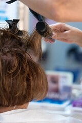 Young hairdresser combing her client's hair