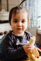 Cute baby eating banana. Cute little girl eating fruit. Healthy snack, food